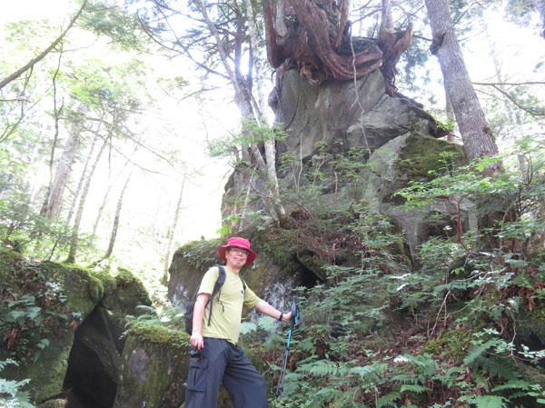 photo：岩穴（左）を潜ると岩の上に巨木・まが玉の丘